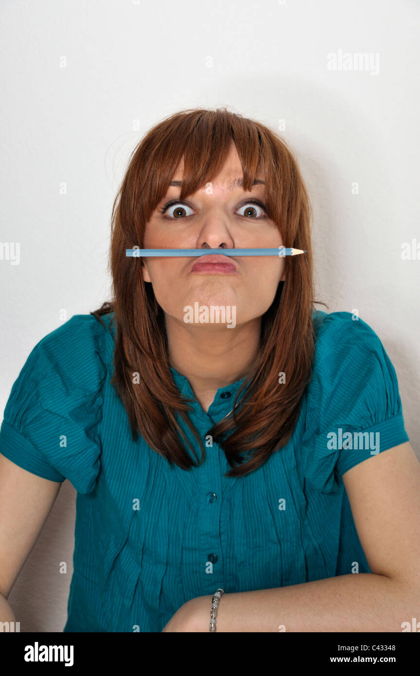 Jeune femme avec crayon entre lèvre et nez Banque D'Images