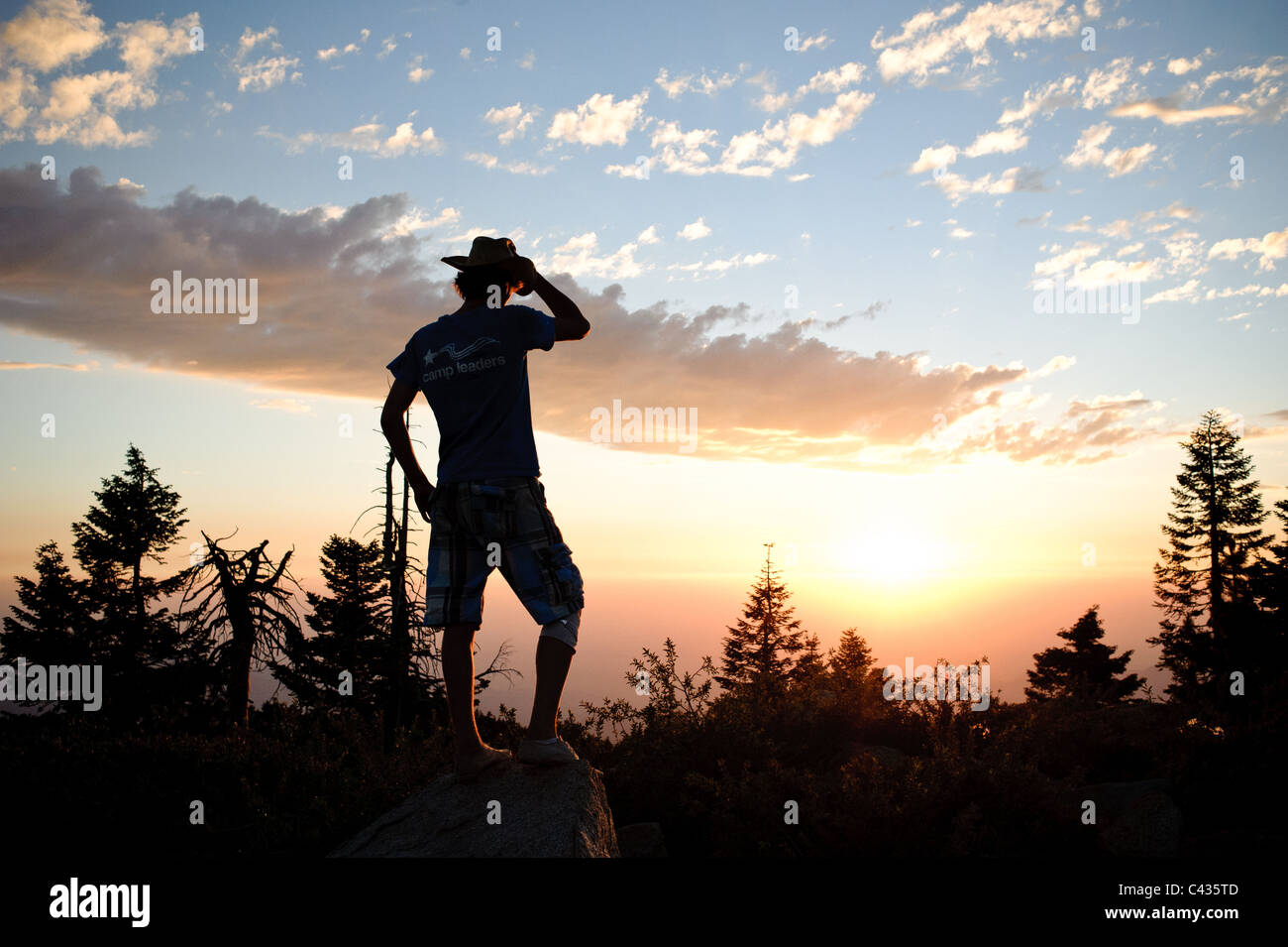 Homme avec chapeau de cowboy au coucher du soleil Banque D'Images