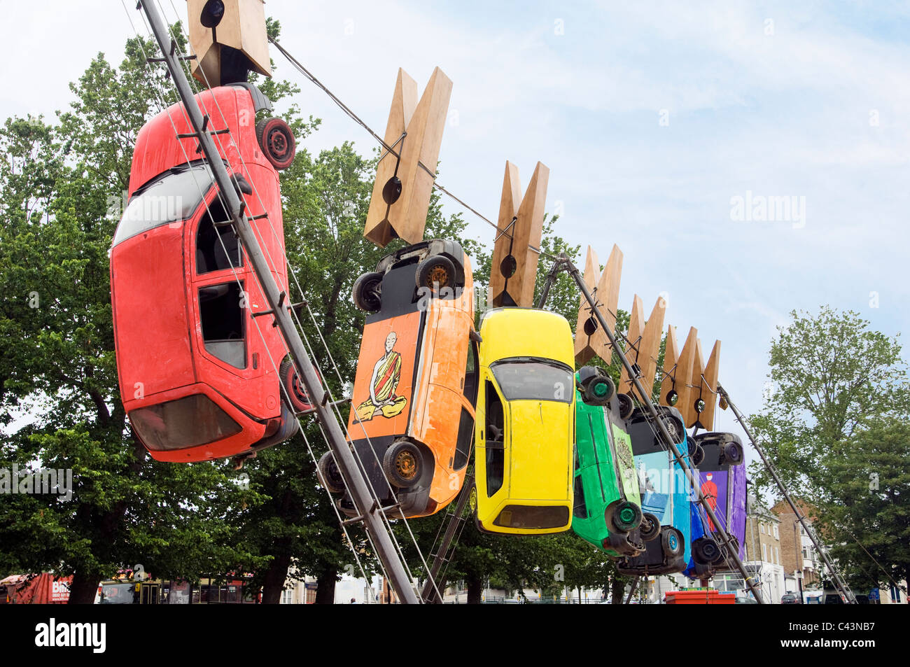 Sept voitures se suspendre à des pinces à linge géantes sur un fil à Brighton dans le cadre du Fringe Festival annuel d'art du théâtre de rue. Banque D'Images