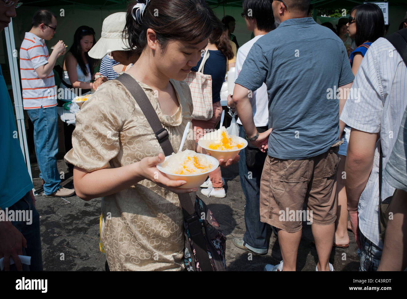 Les visiteurs du festival Passeport pour Taïwan à Union Square Park à NY manger des plats traditionnels de shaved ice avec garniture mangue Banque D'Images