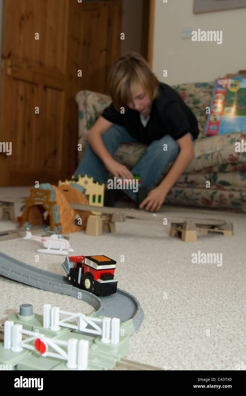 Teenager Playing with toy train et la voie dans une salle de réception dans une maison Banque D'Images