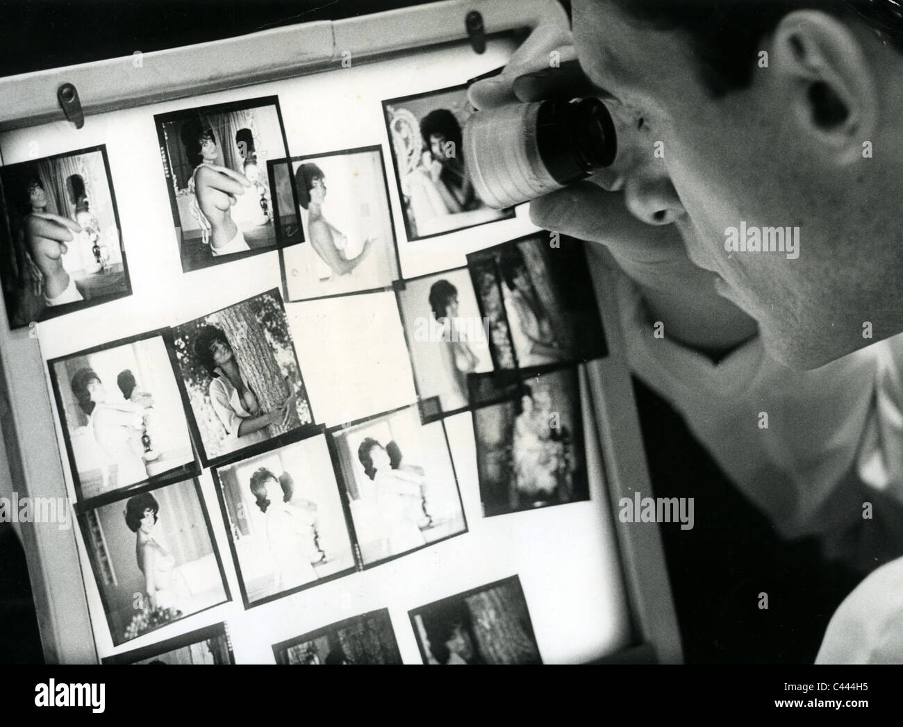 HUGH HEFNER sur 1965 vérifie les transparents en couleur d'un modèle d'être publié dans son magazine Playboy Banque D'Images