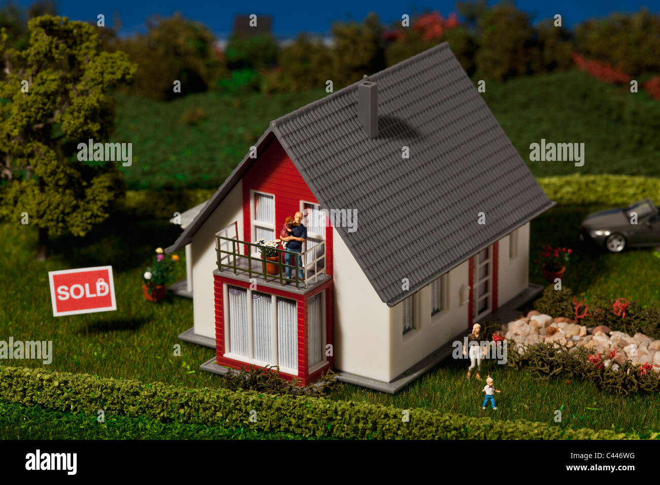 Un diorama d'une maison miniature avec une famille de figurines et un SOLD sign Banque D'Images