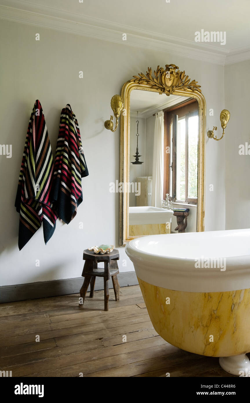 Baignoire en marbre sur pied dans la salle de bains avec parquet et grand miroir doré Banque D'Images