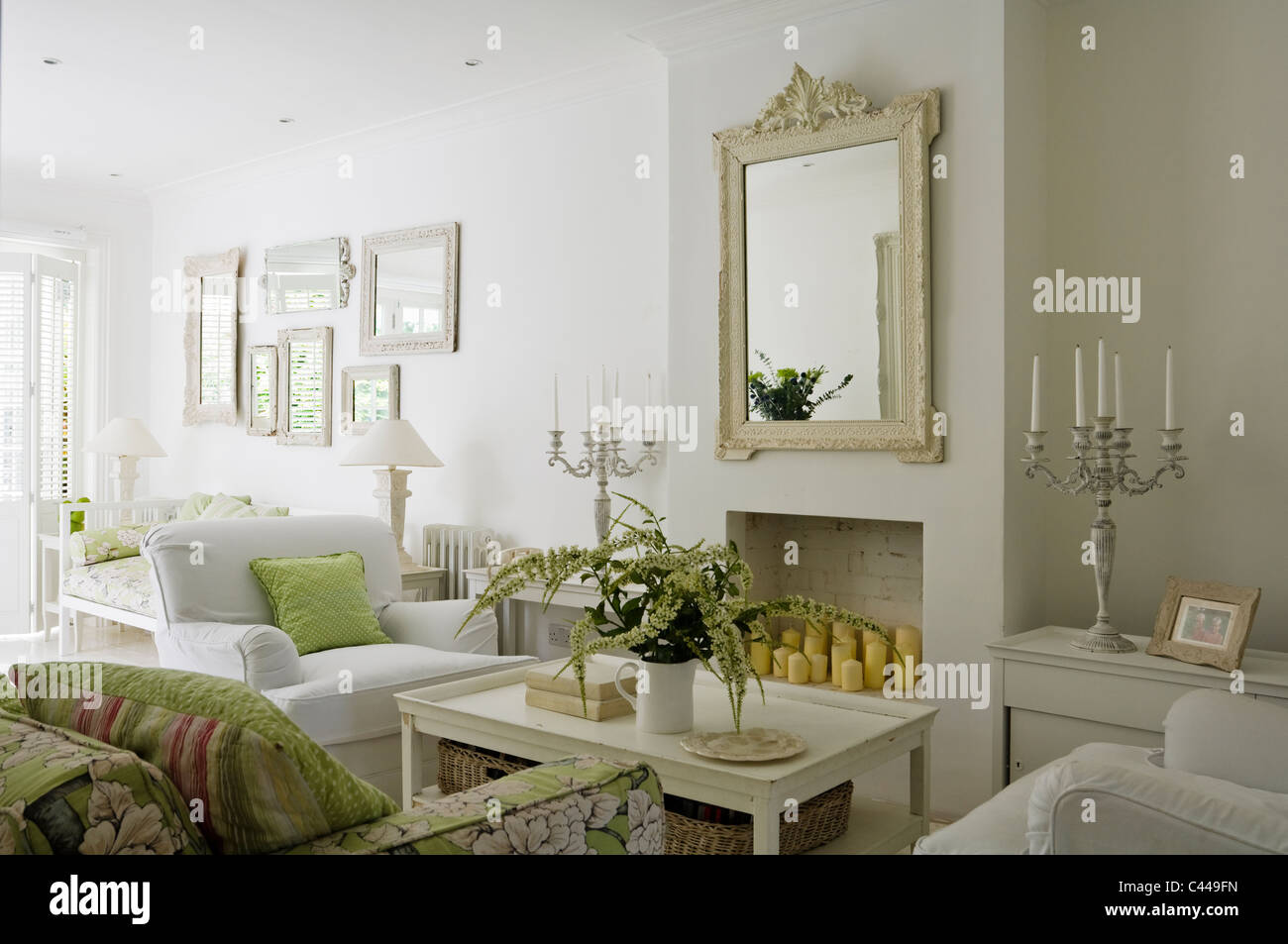 White salon avec table basse, miroir et un canapé à motifs floral. Banque D'Images