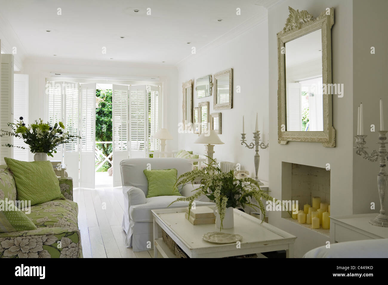 White salle de séjour avec cheminée, miroir, arrangements de fleurs et de fauteuils Banque D'Images