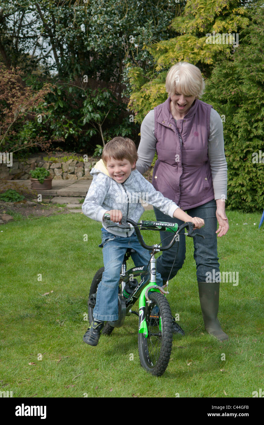 L'enseignement de la grand-mère petit-fils à faire du vélo dans un jardin arrière Banque D'Images