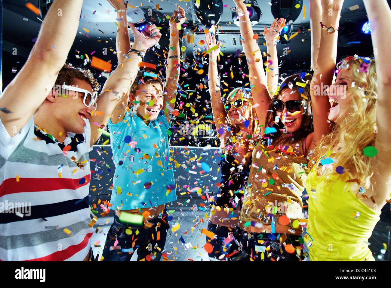 Photo d'adolescents excités levant les bras sous les confettis Banque D'Images