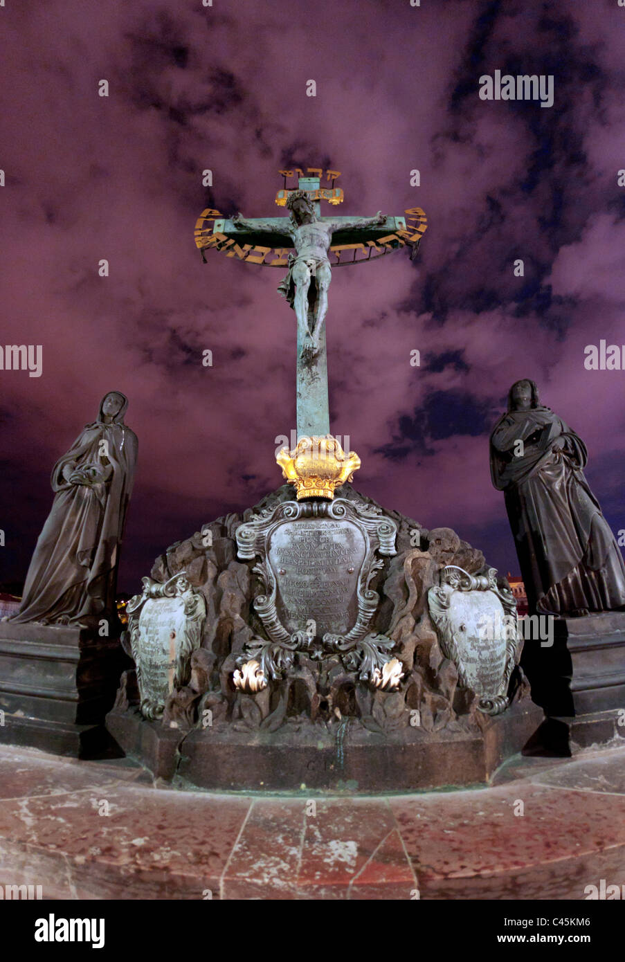 Statue de Jésus crucifié sur le pont Charles à Prague République tchèque, avec ciel de nuit et les nuages. Banque D'Images