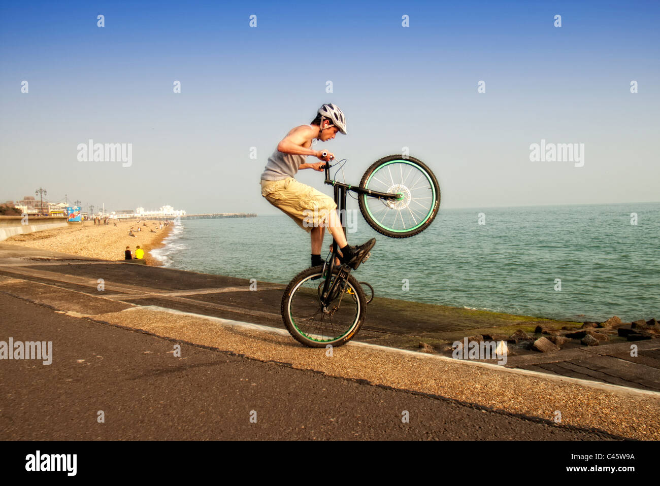 Jeune homme faisant wheelie astuces sur son vélo BMX stunts Banque D'Images