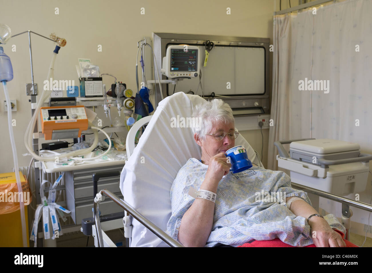 Femme attaque cardiaque patient boire le thé de la récupération à l'unité de réanimation en cas d'accident et d'urgence d'un hôpital. Pays de Galles UK Banque D'Images