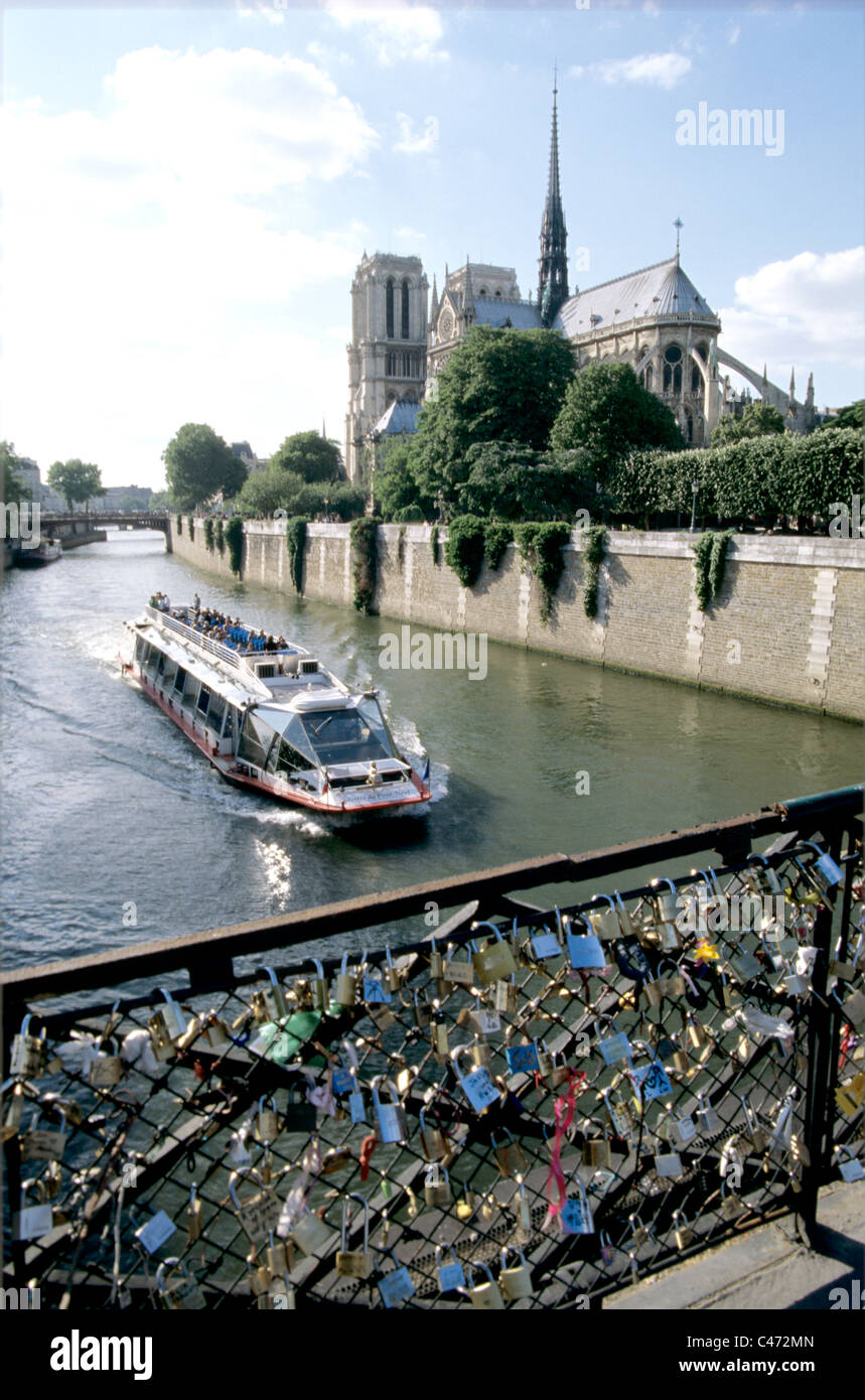 Vue du pont orné de serrures et les amoureux de bateau d'excursion sur la seine passé à la Cathédrale Notre Dame Banque D'Images