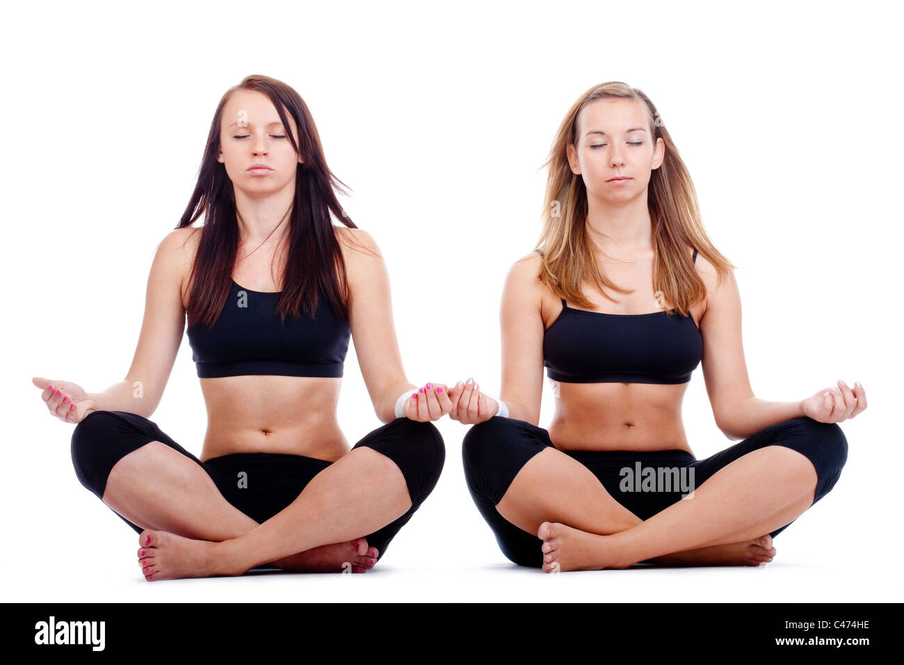 Deux jeunes femmes assises sur le sol l'exercice de yoga - isolated on white Banque D'Images