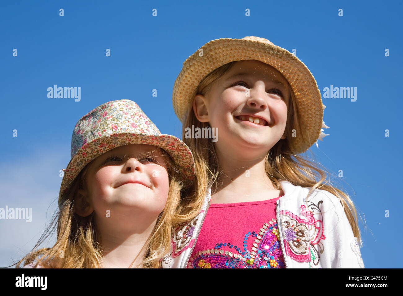 Portrait de deux soeurs âgés de sept et quatre ans contre un fond de ciel bleu d'été Banque D'Images