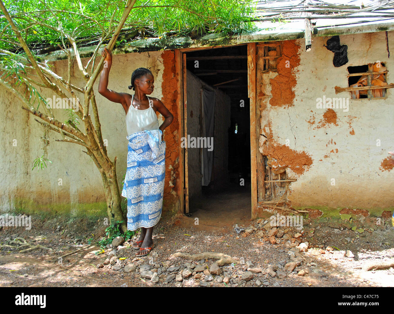 Femme debout par sa maison dans les régions rurales de Côte d'Ivoire Banque D'Images