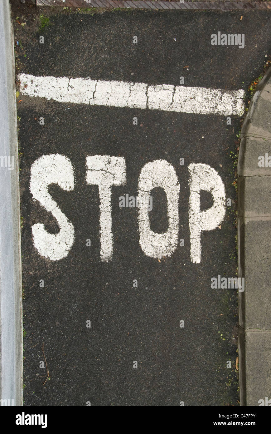 Panneau stop et écrit à la main en ligne blanche sur une petite route goudronnée ou blacktop Banque D'Images