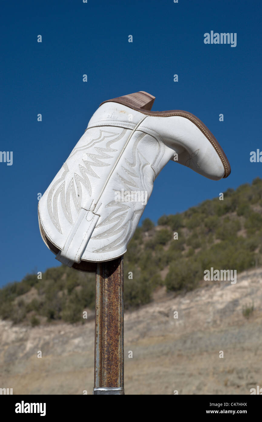 Un cowboy boot bloqué sur un poste est un signe de l'humour, de l'Ouest dans le comté de Lincoln, au Nouveau-Mexique. Banque D'Images