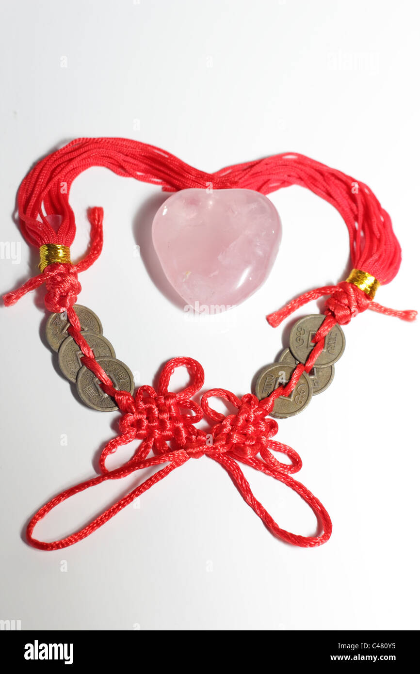 Vue horizontale d'un coeur formé de deux noeuds chinois avec un cristal de couleur rose Banque D'Images