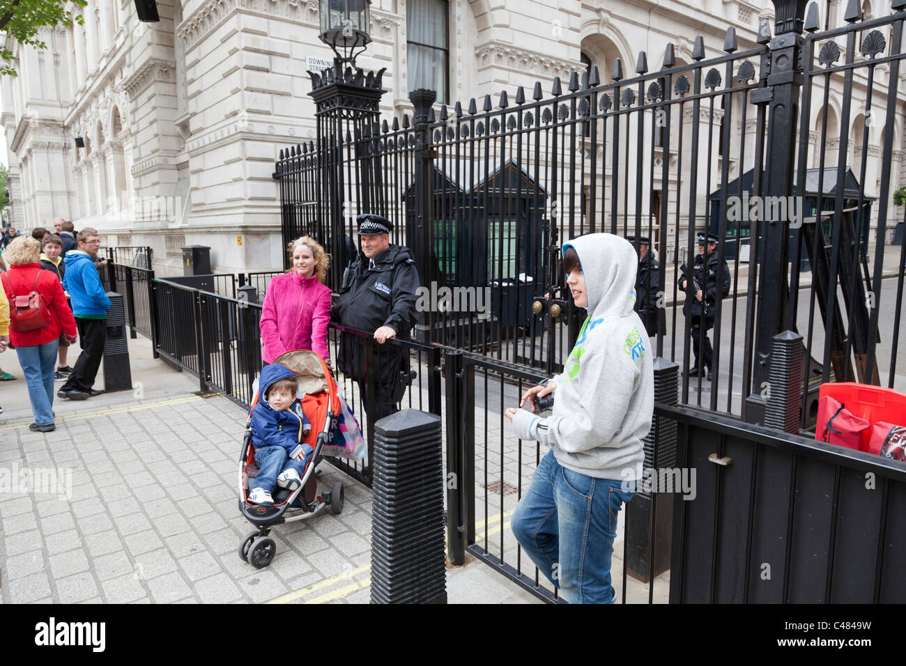 Des touristes posent pour la photographie aux côtés d'un policier en dehors de Downing Street, Londres. Banque D'Images