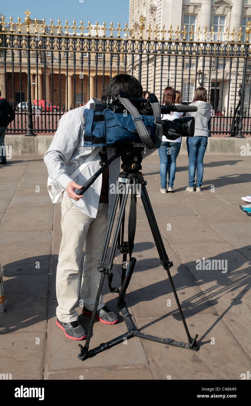 Un caméraman de la télévision qui travaillent à l'extérieur du garde-corps à Buckingham Palace, London, UK avant le mariage royal 2011. Banque D'Images