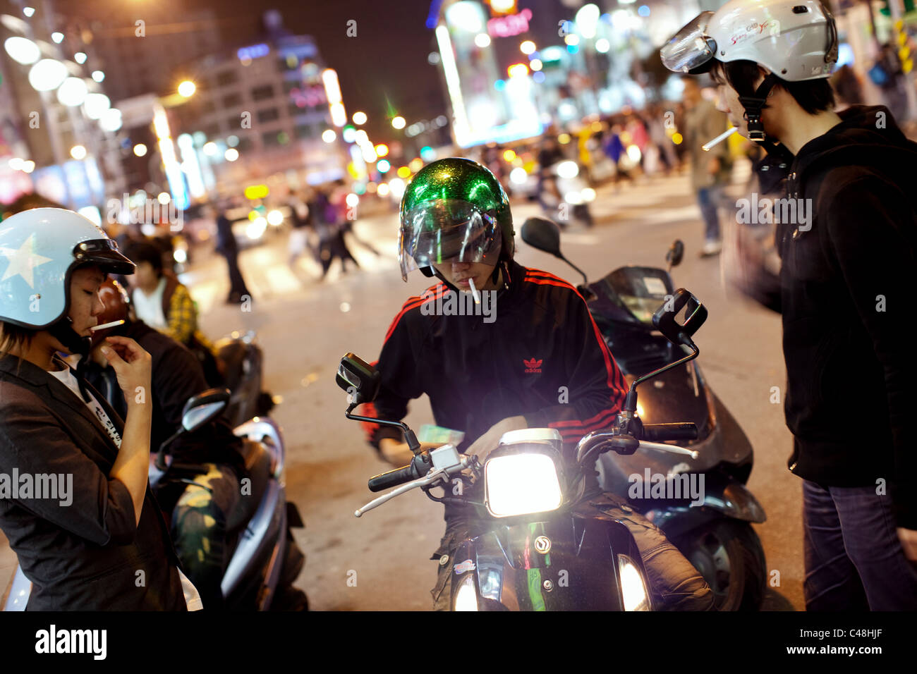 Les jeunes hommes s'arrêtent sur leurs trottinettes et rendez vous pour une fumée dans Ximending, Taipei, Taiwan, le 7 novembre 2010. Banque D'Images