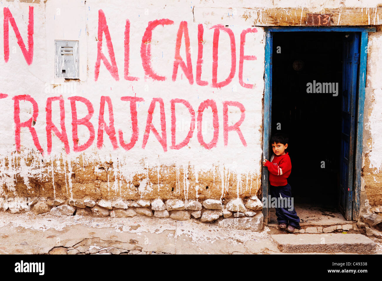 Un jeune garçon se tient dans l'embrasure d'graffiti ,en espagnol, dans la ville de Mollepata,début de la randonnée de Salkantay à Machu Picchu, Pérou Banque D'Images