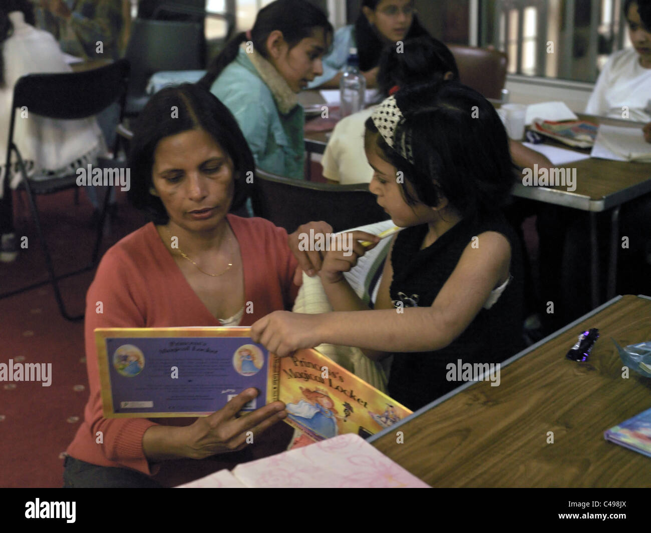 Centre hindou hindou Londres Angleterre Wimbledon School Teacher Helping Girl pour lire un livre Banque D'Images