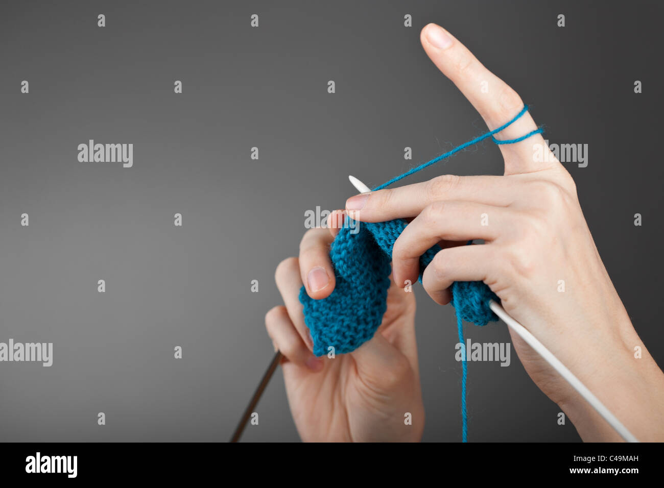 Mains d'une jeune femme le tricot avec la laine bleu Banque D'Images