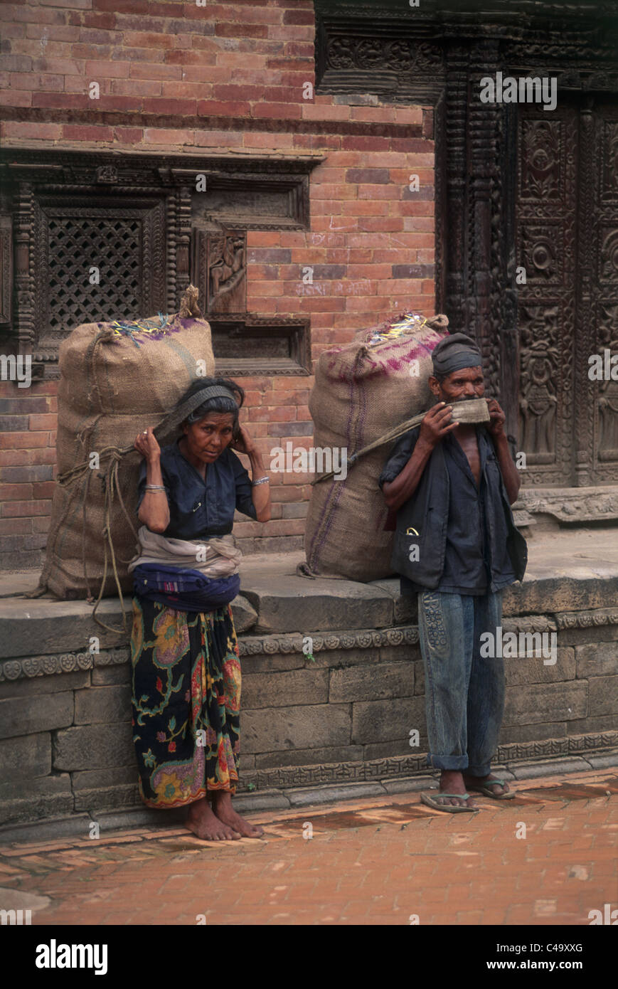 Photo d'un homme et une femme realiser une grande charge sur leur dos au Népal Banque D'Images