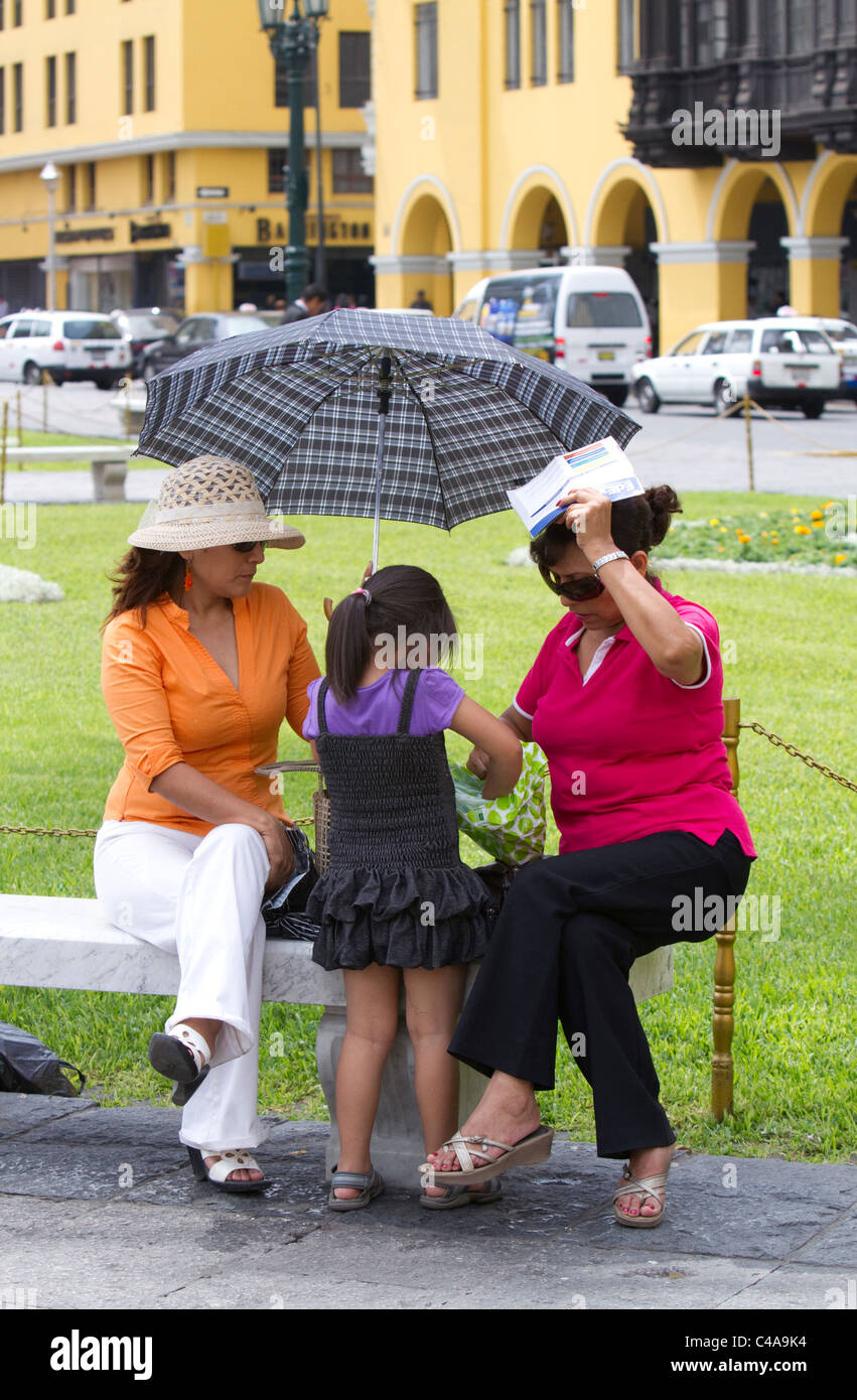 L'ombrage des femmes elles-mêmes de la chaleur du soleil avec un parapluie à la Plaza Mayor et la Plaza de Armas de Lima, Pérou. Banque D'Images