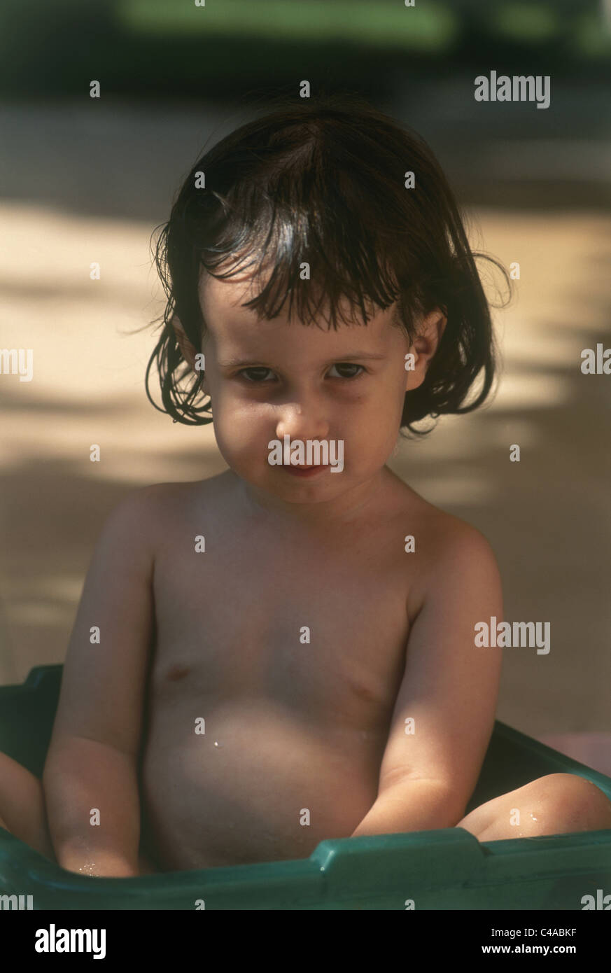 Un enfant assis dans une baignoire Banque D'Images