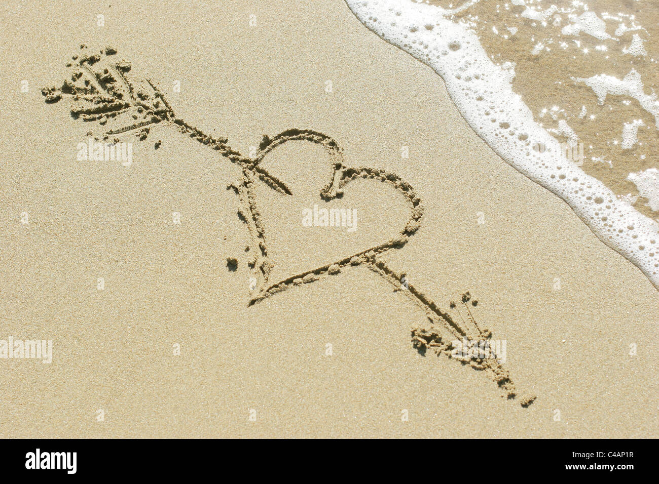 Cœur percé par la flèche de Cupidon dessiné dans le sable Banque D'Images