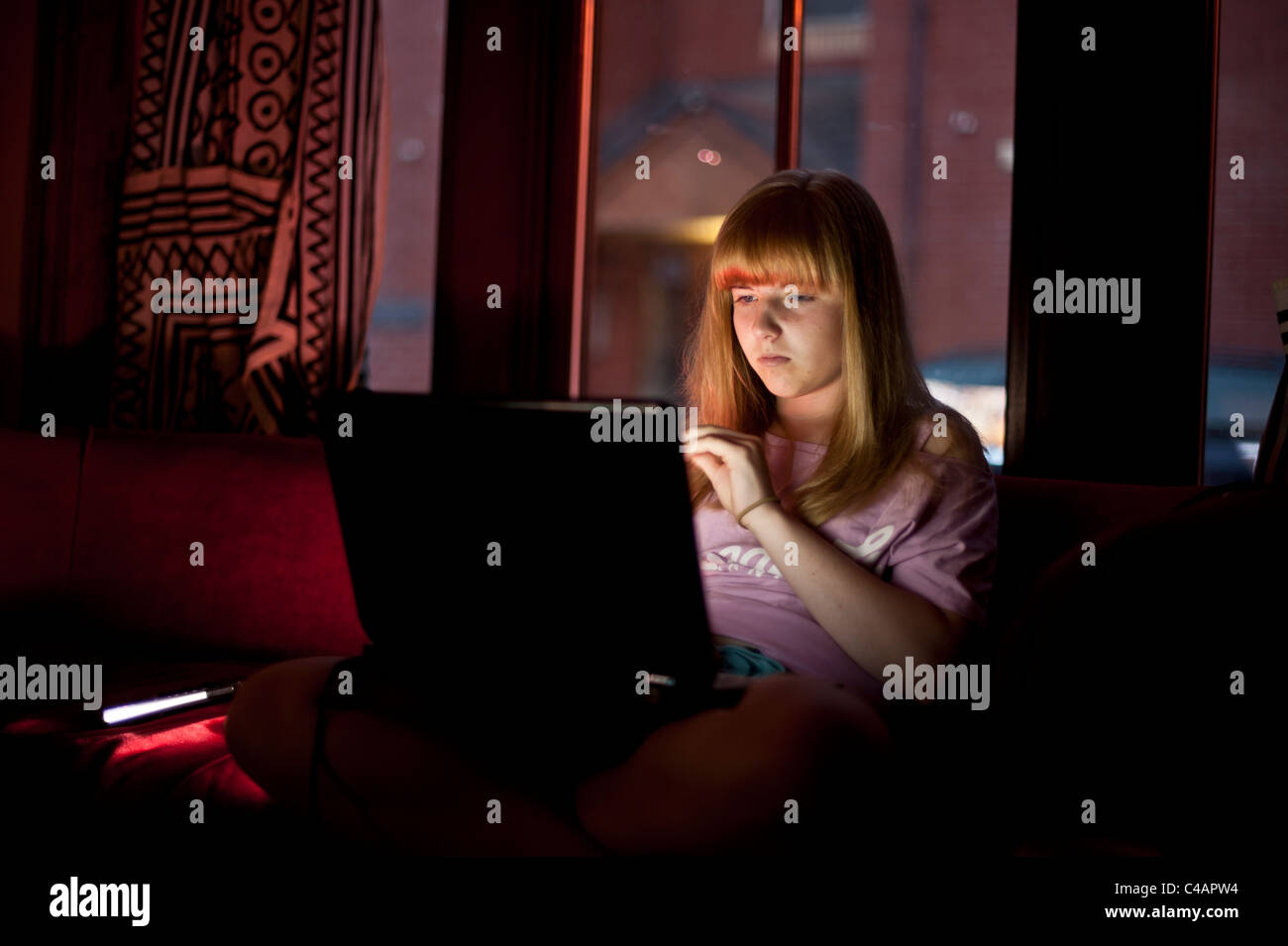 Une adolescente vérification du courrier électronique le réseau social FACEBOOK sur son ordinateur portable à la maison soir uk Banque D'Images