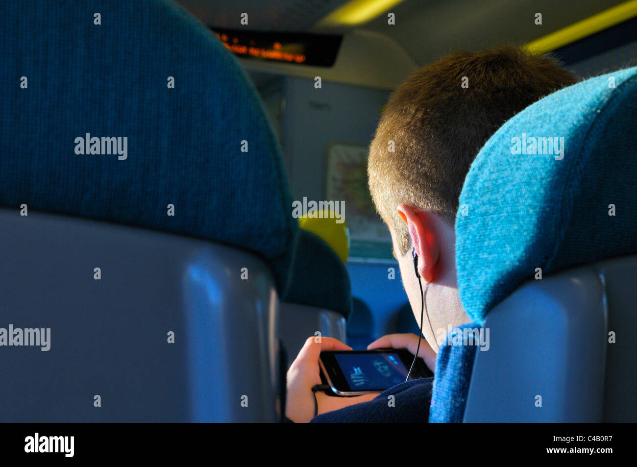 Jeune homme passant le temps sur un voyage en train avec un film sur son smartphone Banque D'Images