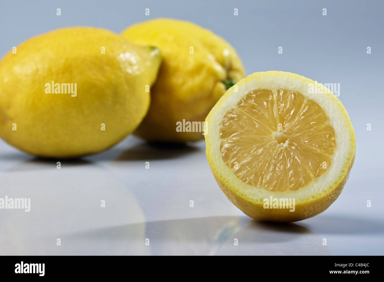 Still Life close up d'un demi citron avec une paire de citrons contre un fond uni Banque D'Images