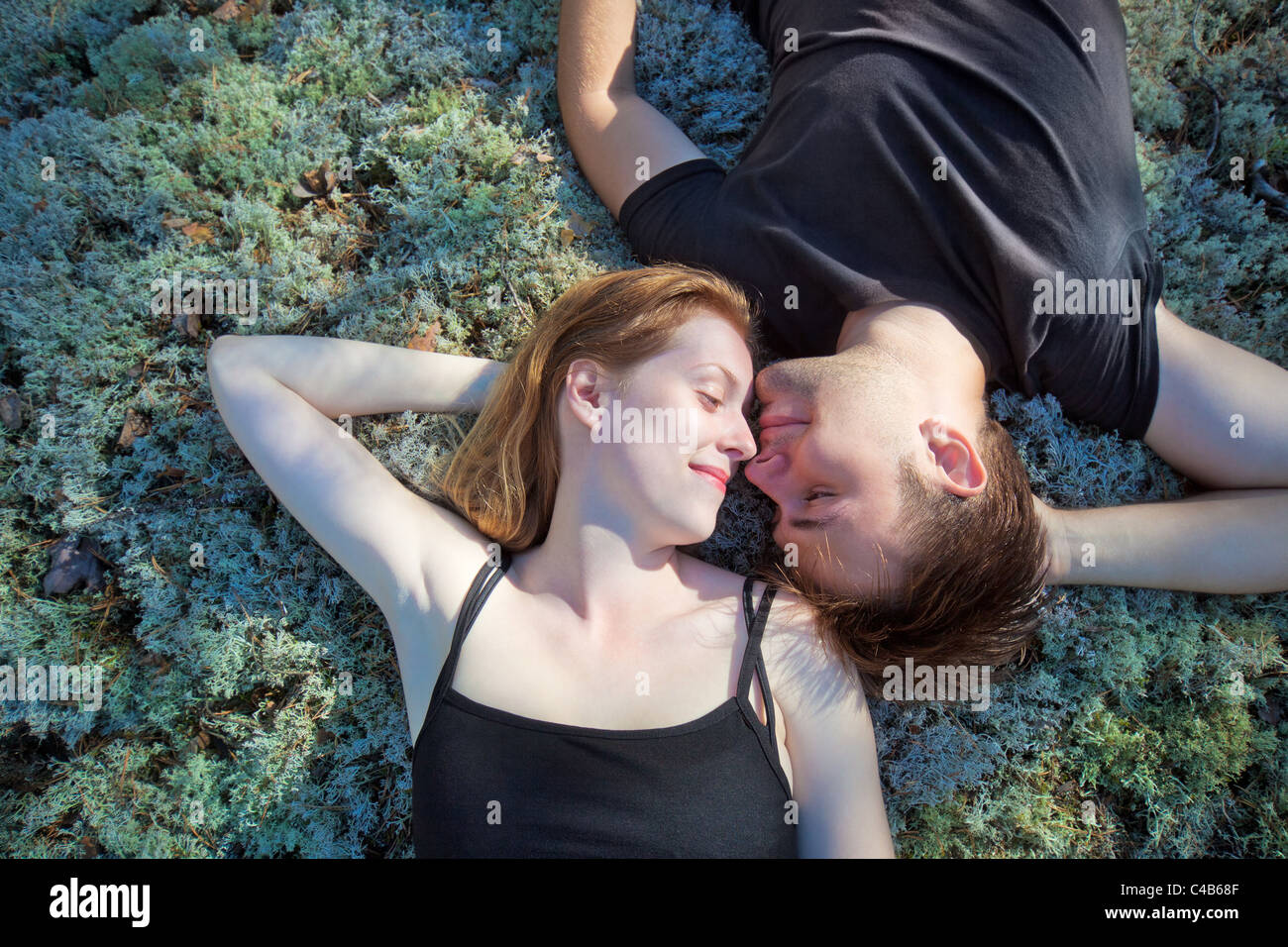 Jeune couple reposant sur l'herbe dans la forêt. Banque D'Images