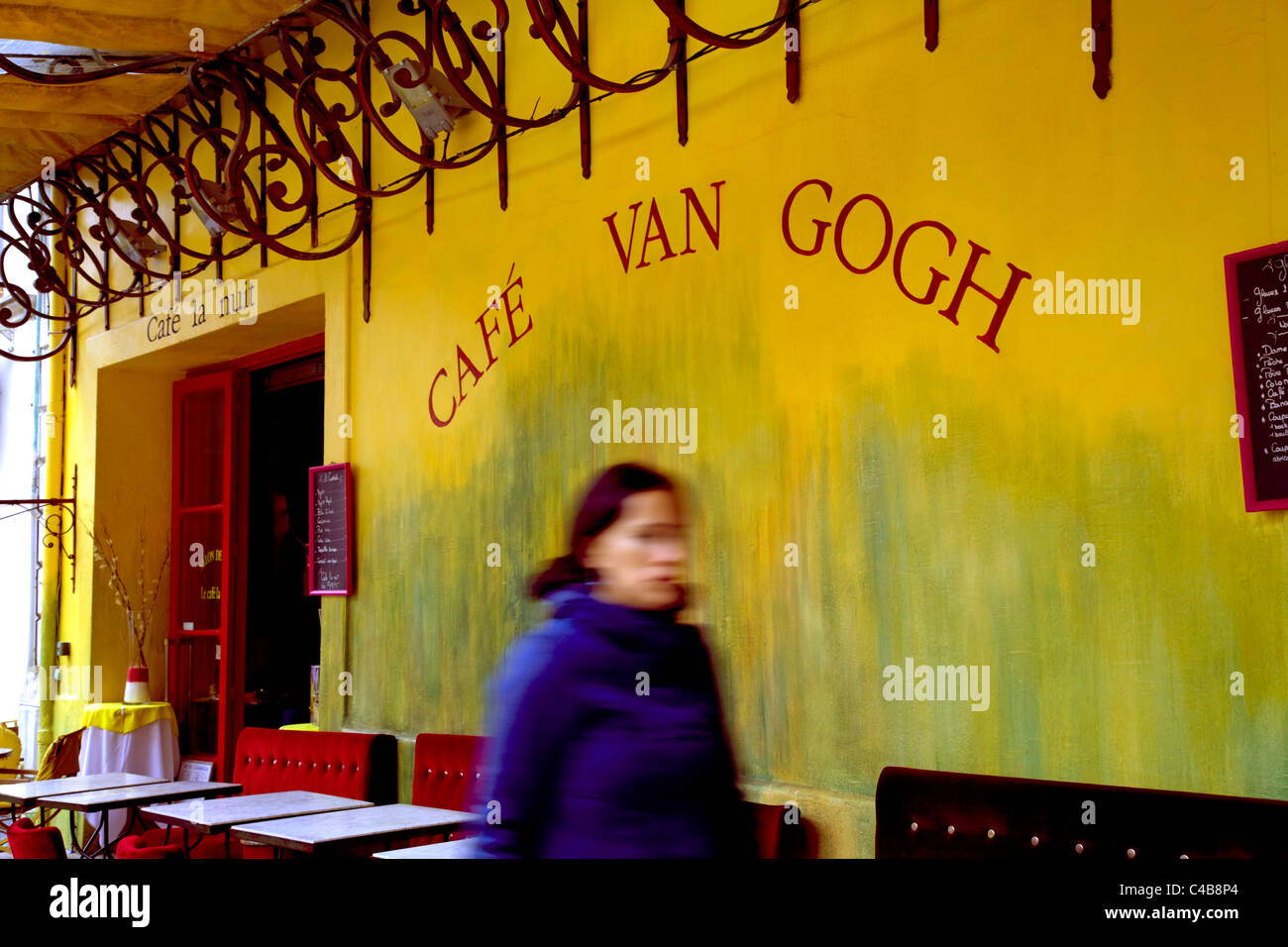 Arles, Bouches du Rhône, France ; une jeune femme marche en face de l'ancienne terrasse de café Banque D'Images