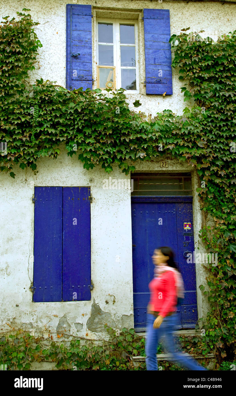 Arles, Bouches du Rhône, France ; une jeune femme marchant devant une maison aux couleurs vives. M. Banque D'Images