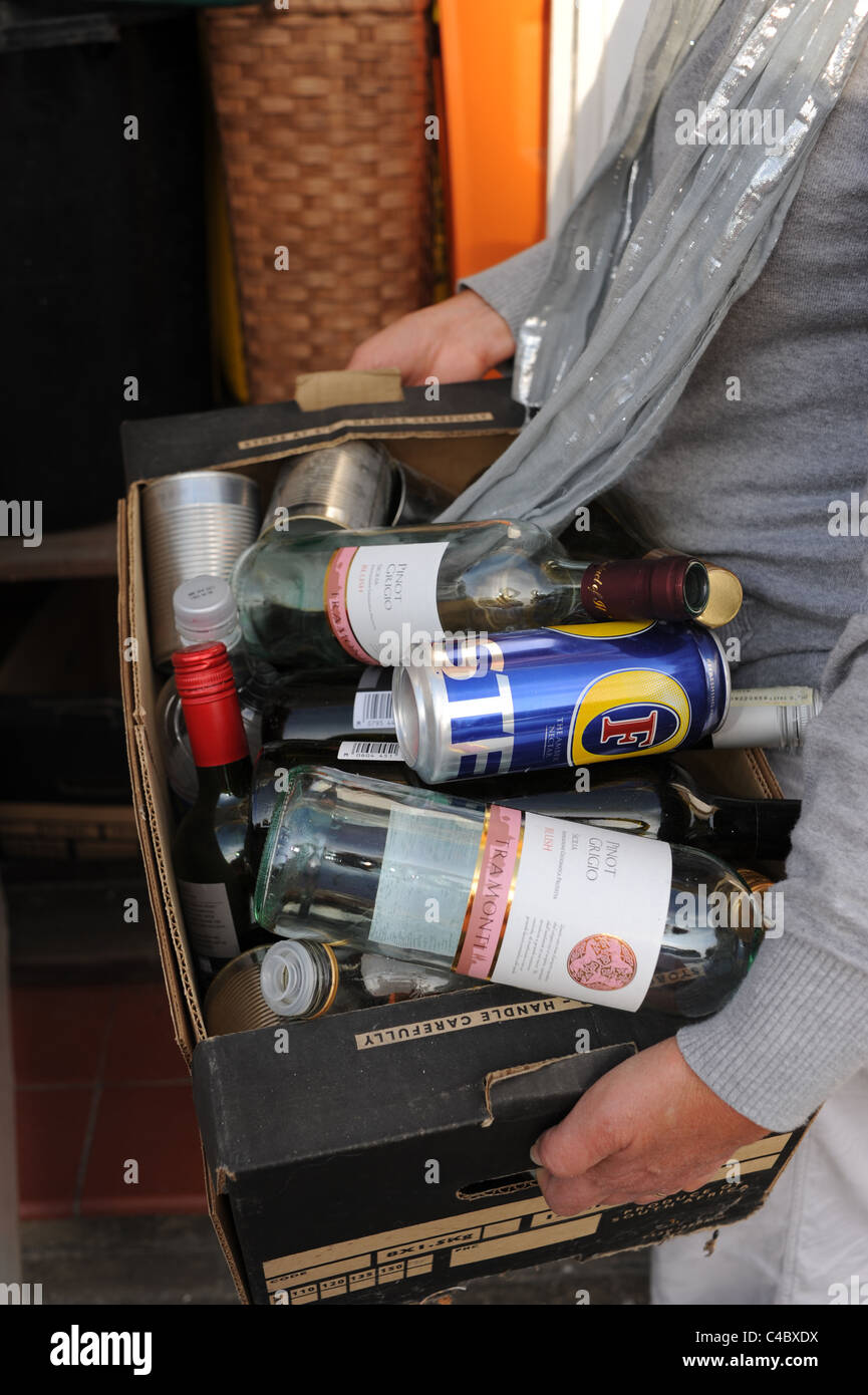 Femme d'âge moyen avec une boîte de bouteilles et boîtes de recyclage au Royaume-Uni Banque D'Images