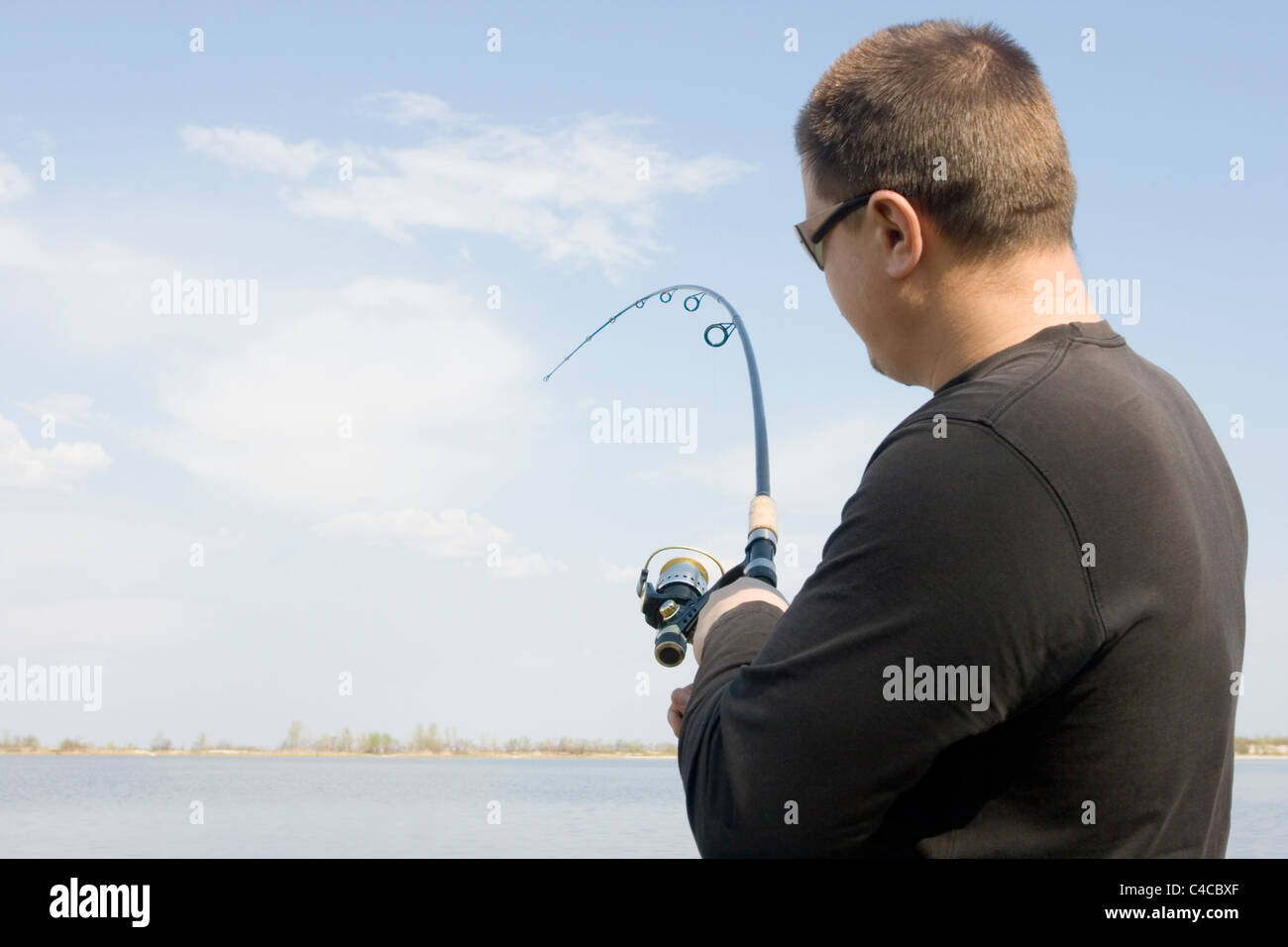 Pêcheur tenant une canne de la pêche sur le lac. Banque D'Images