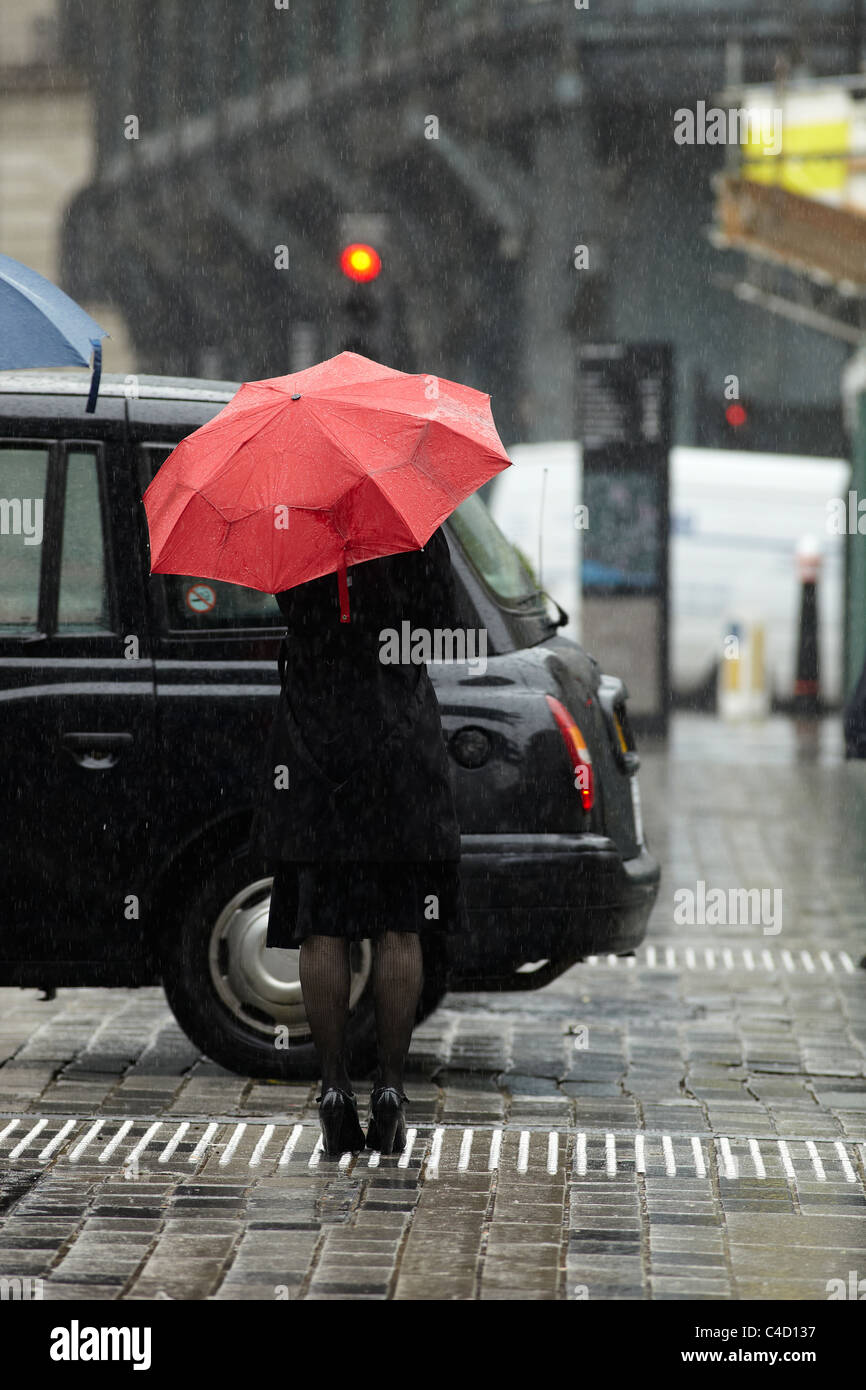 Travailleur de la ville de Londres dans la pluie holding red umbrella dans Queen Street, Londres UK. Banque D'Images