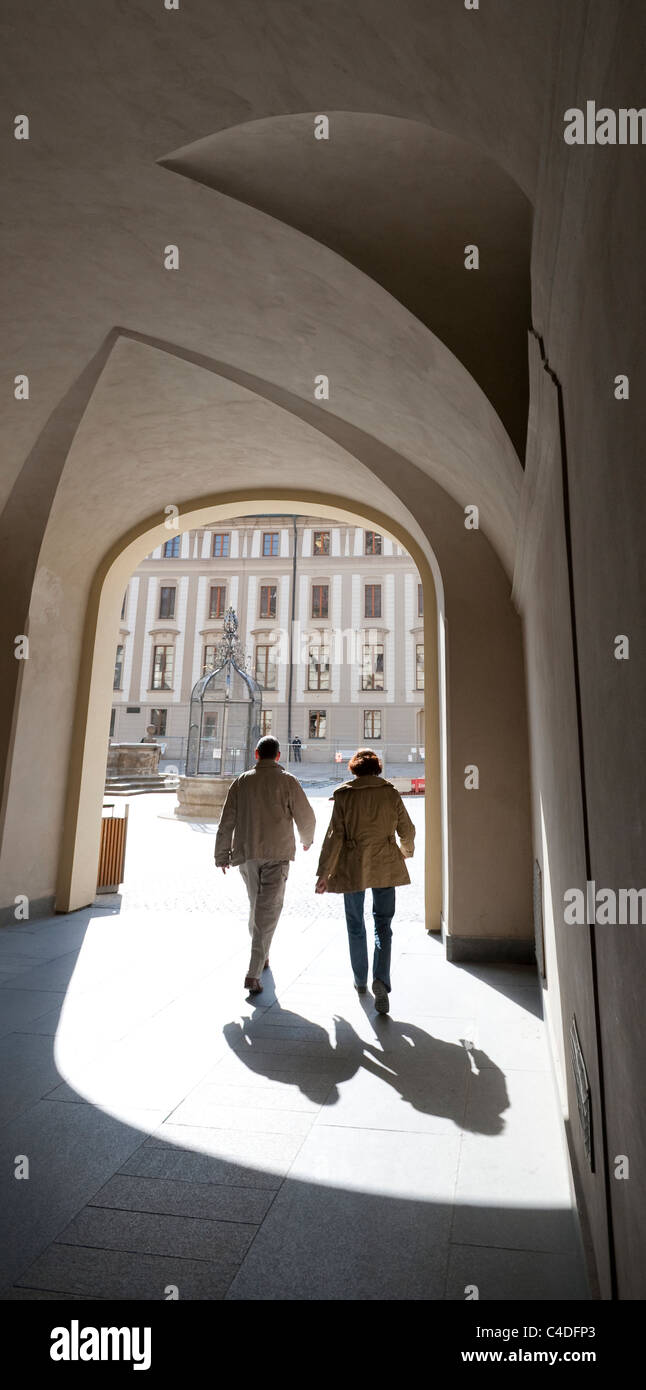 Un couple qui se profile par le soleil du printemps marche à travers une arche à la présidence de la République au Château de Prague Banque D'Images