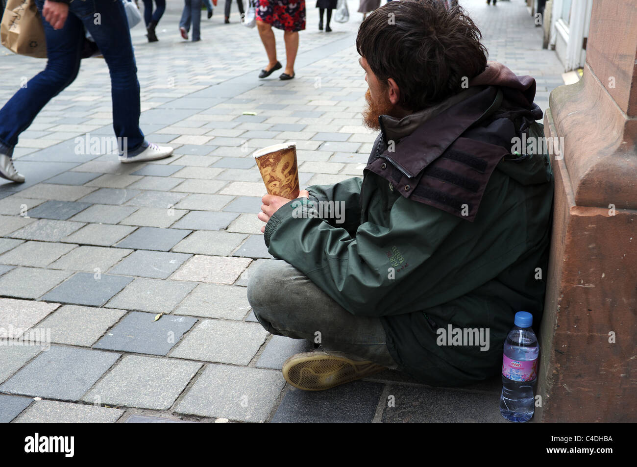 Homme assis et mendier dans la rue Sauchiehall Street, Glasgow, Écosse, tandis que les gens de l'ignorer et à pied par Banque D'Images