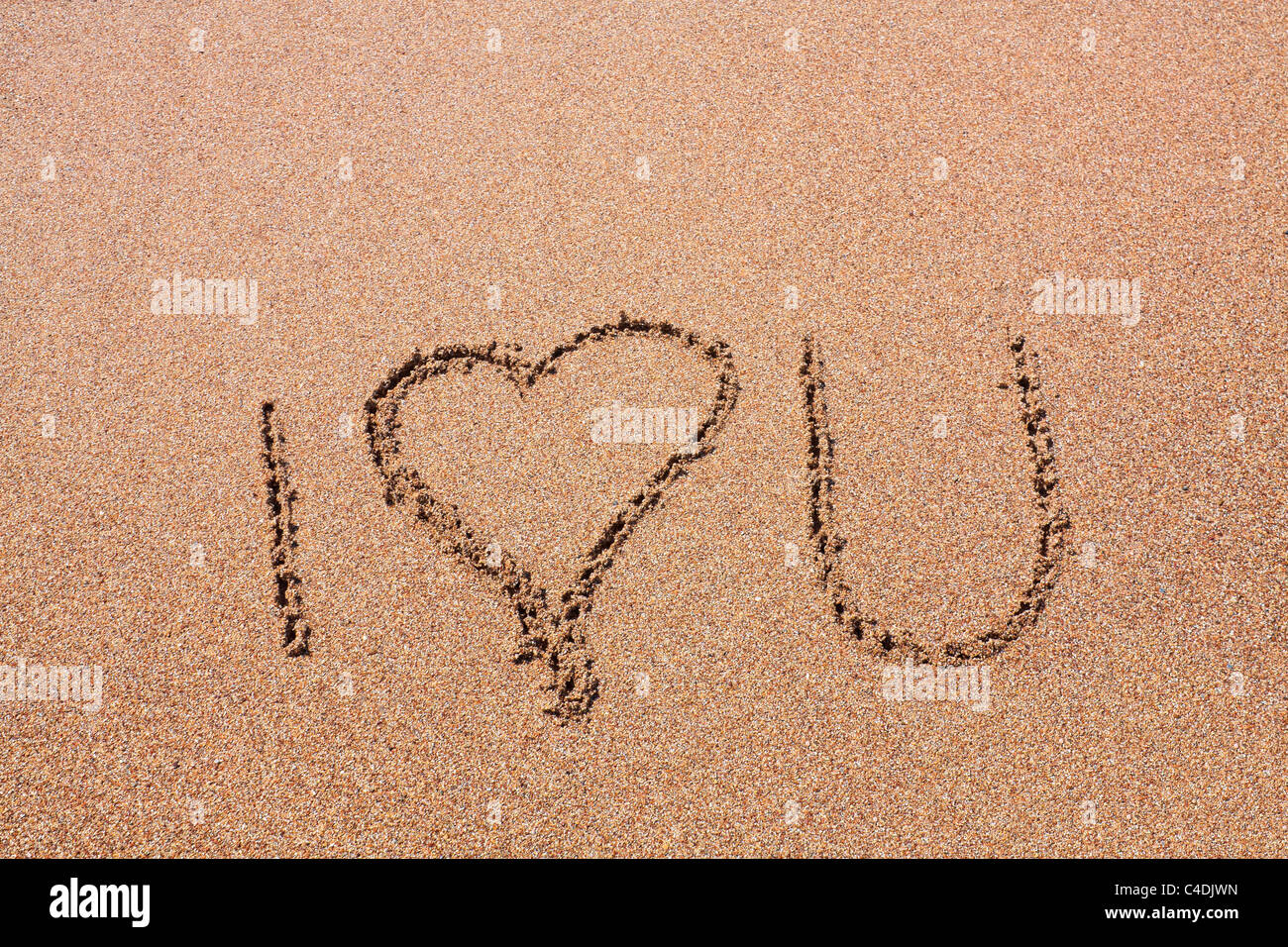 "I love u' écrit sur le sable brun contre un fond texturé Banque D'Images