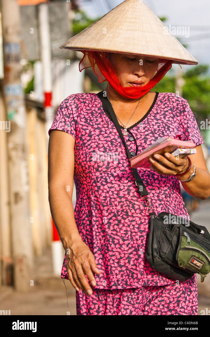 Femme portant chapeau conique vente de billets de loterie Banque D'Images