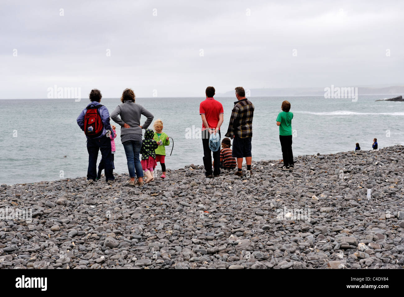 Personnes debout face à la mer sur les pierres de Northcott Mouth à North Cornwall, UK Banque D'Images