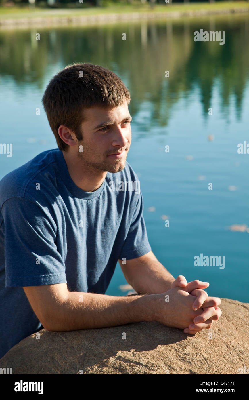 15-18 ans ans jeune homme méditant et priant seul réfléchie en parc. M. © Myrleen Pearson Banque D'Images