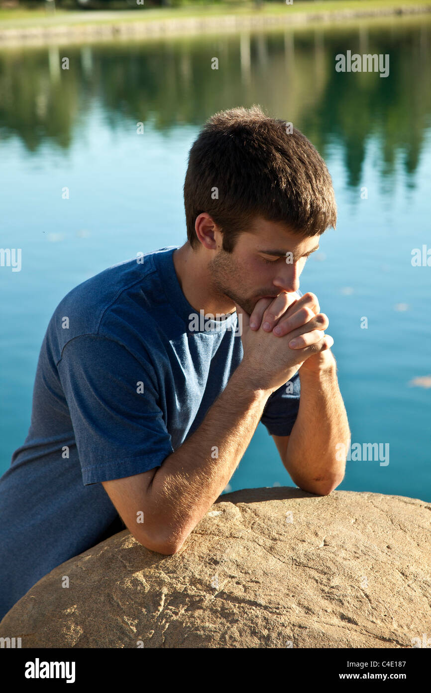 16-18 ans ans jeune homme méditant prie et réfléchie dans le seul parc. nature, environnement naturel thoughtful rêver assis MR ©  = = Banque D'Images
