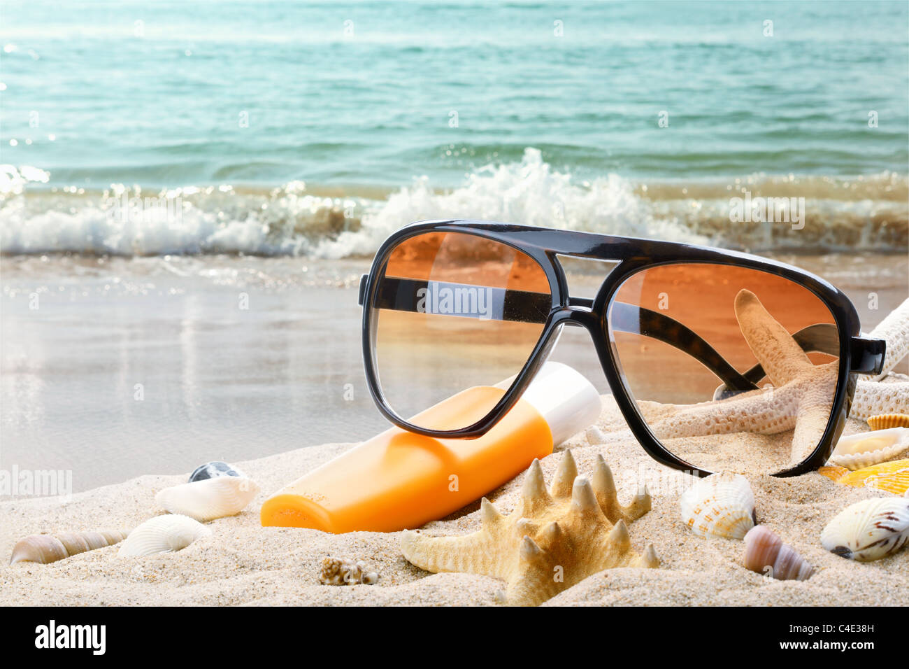 Les lunettes de soleil et une bouteille de baume solar sur une plage de  sable Photo Stock - Alamy