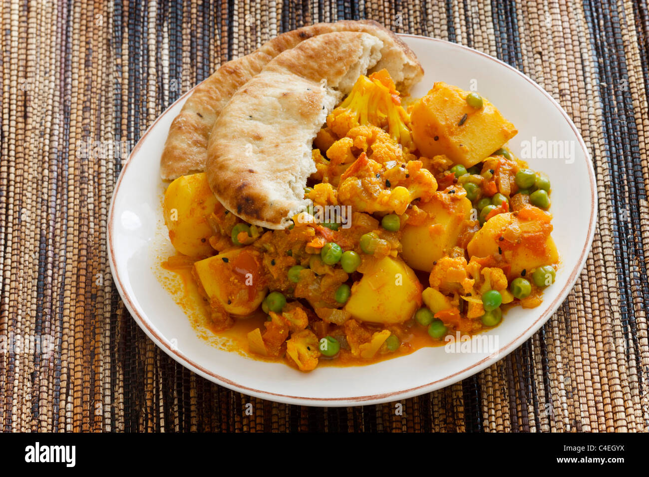 Curry végétarien indien fait à partir de chou-fleur, les pommes de terre et les pois, servi avec du pain naan. Banque D'Images